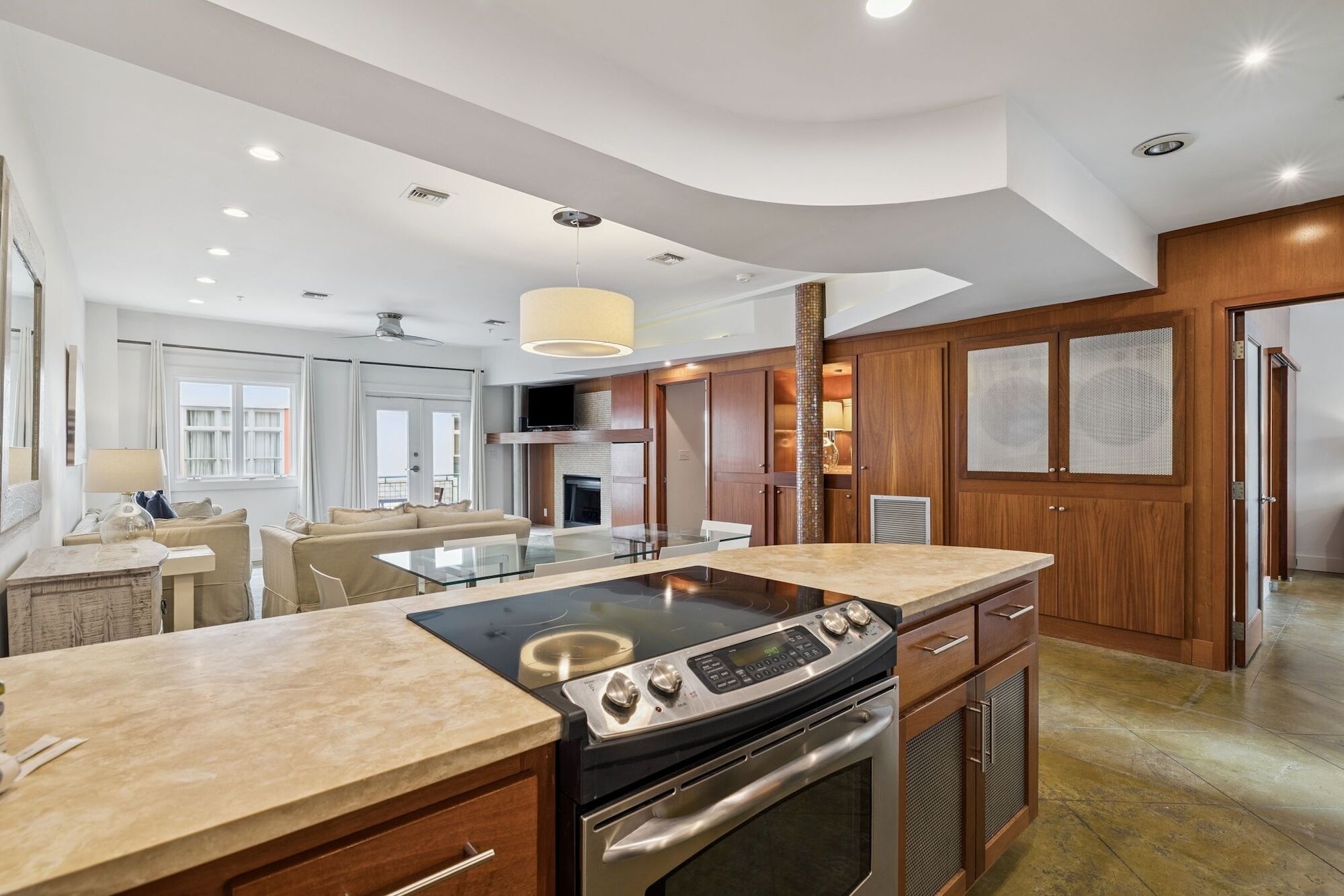 A modern kitchen with a central island, built-in oven, and a dining area with a glass table.