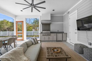 A modern kitchen with a built-in grill, a dining area with a wooden table and chairs, and a cozy seating area with a sofa and patterned cushions. - Close to the Town Square w/ Pool and LSV (Seacrest Beach)