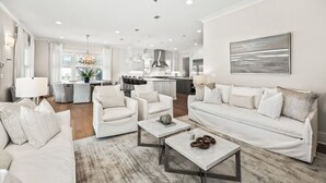 A modern living room with white furniture, a marble coffee table, and a view into the kitchen. - Close to the Town Square w/ Pool and LSV (Seacrest Beach)