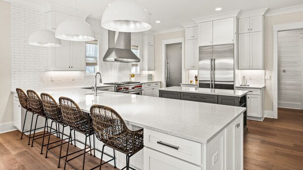 A modern kitchen with white cabinetry, a large island with bar stools, stainless steel appliances, and pendant lighting. - Close to the Town Square w/ Pool and LSV (Seacrest Beach)