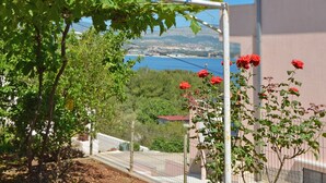 A garden with a pergola, red roses, and a view of a coastal town. - TANJA 1 - 1 bedroom apartment, 200m from the beach in Slatine (Slatine)