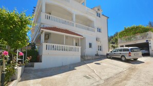 A multi-story building with balconies, a car parked in front, and a clear blue sky. - TANJA 1 - 1 bedroom apartment, 200m from the beach in Slatine (Slatine)