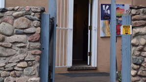 Un muro de piedra con una verja de madera y una puerta que da a un edificio.