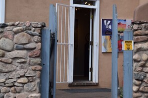 A stone wall with a wooden gate and a door leading into a building. - Escape into serenity just minutes from the Plaza. Hot tub and sauna. (Santa Fe)