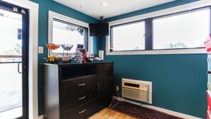 A room with teal walls, a dark wooden dresser, a window with a view, and a small heater on the floor. - Hotel O Kissimmee West - US 192 (Kissimmee)