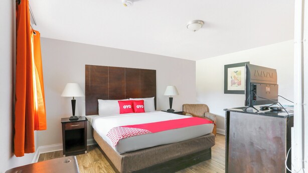A hotel room with a large bed, two bedside tables with lamps, a desk with a computer, and a TV. - Hotel O Kissimmee West - US 192 (Kissimmee)