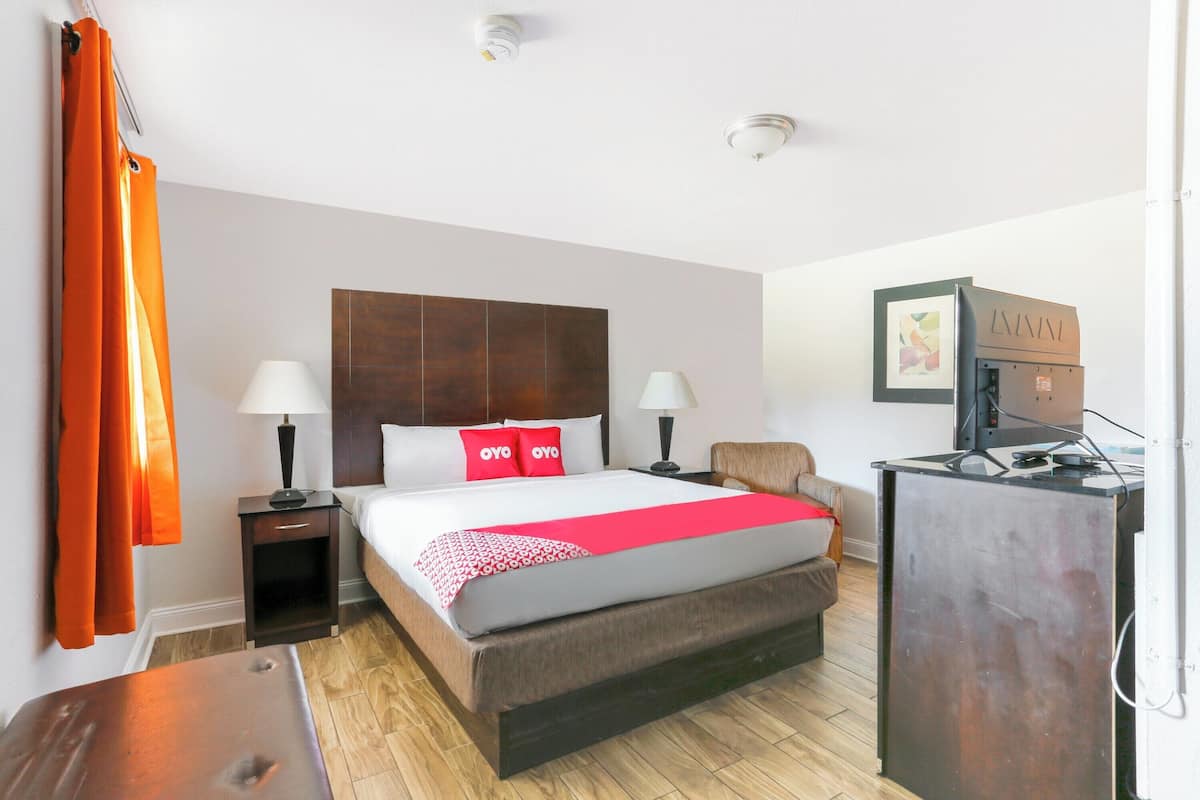 Habitación de hotel con una cama grande, dos mesitas de noche con lámparas, un escritorio con computadora y una televisión.