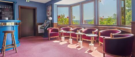A room with a bar, seating area, and large windows offering a view.