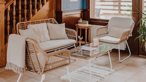 Una sala de estar acogedora con muebles de mimbre, una escalera de madera y vistas al exterior.