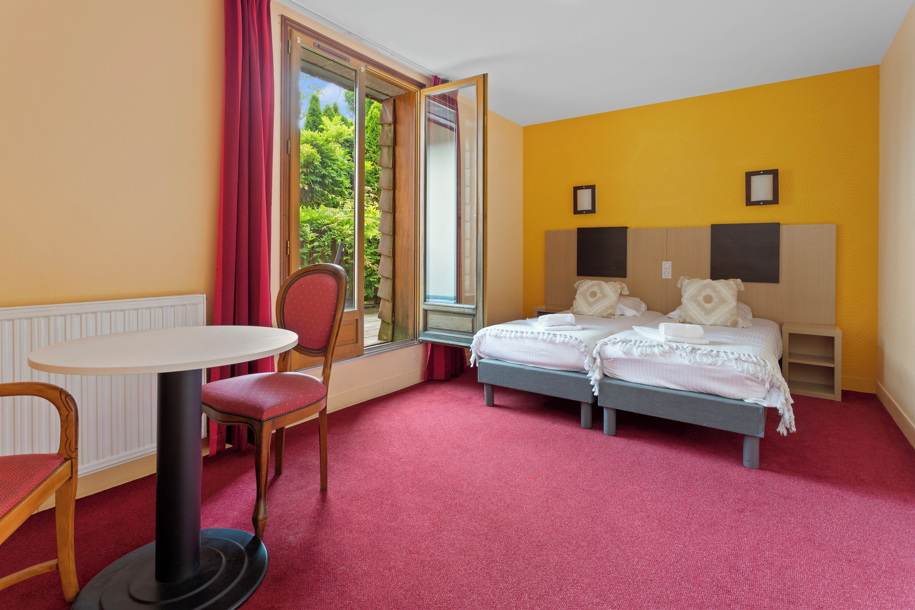 A hotel room with a bed, a table, and a chair.