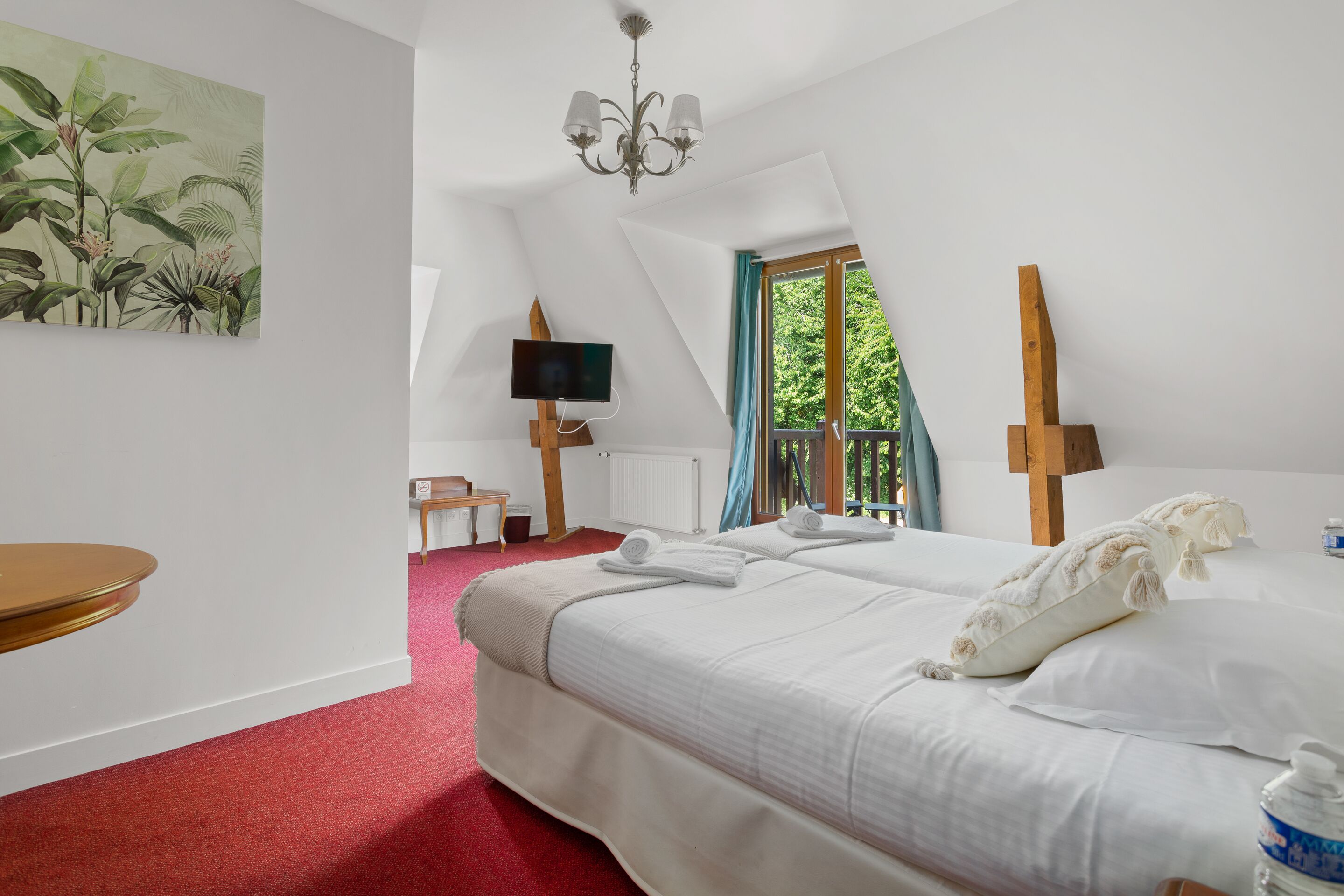 Una camera da letto con un letto grande, una TV, un quadro e una finestra con vista sul verde.