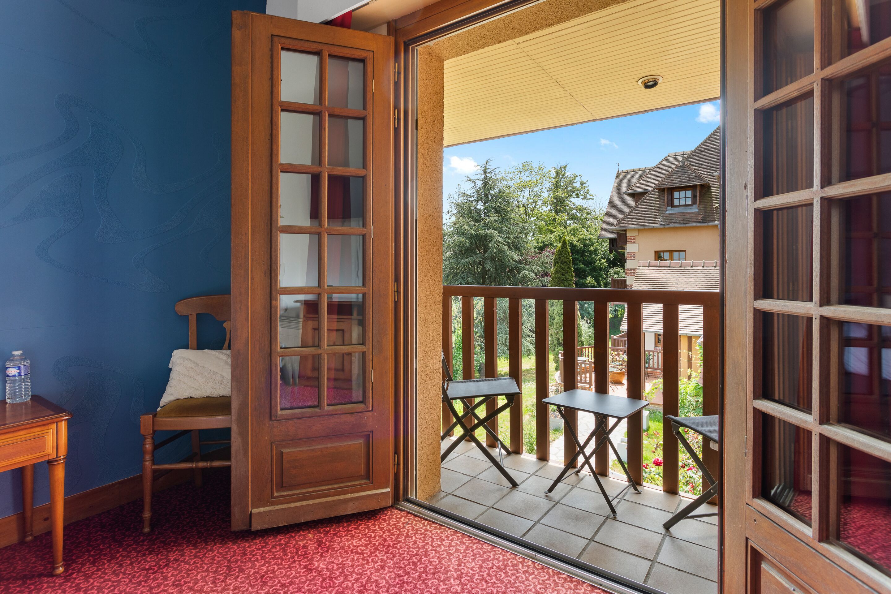 A room with a wooden door leading to an outdoor balcony with a table and chairs.