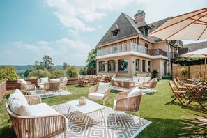 Un patio espacioso al aire libre con mobiliario de mimbre y un tapete estampado, con vistas a un paisaje pintoresco.