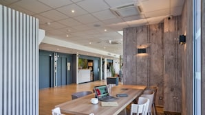 A spacious, modern meeting room with a wooden table, white chairs, and a laptop. - B&B HOTEL Paris Créteil (Creteil)