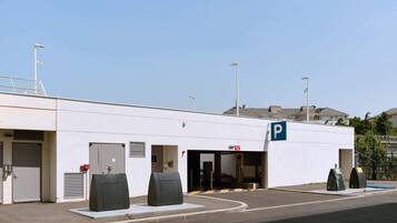 A modern building with a parking entrance, a fire exit, and a covered waiting area.
