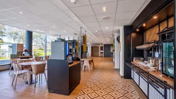 A modern restaurant with a central counter, dining tables, and chairs.