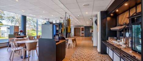 A modern restaurant with a central counter, dining tables, and chairs.