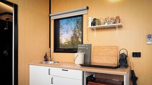 A modern kitchen with a built-in oven, a window with a view, a shelf with jars, and a sign welcoming guests. - Belrose Estate by Tiny Away (Dumbalk)