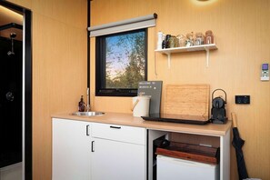A modern kitchen with a built-in oven, a window with a view, a shelf with jars, and a sign welcoming guests. - Belrose Estate by Tiny Away (Dumbalk)