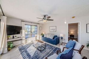 A living room with a TV, sofa, coffee table, and ceiling fan.