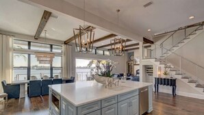 A spacious kitchen with a large island, wooden beams, and a view to the outside.