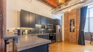 A modern kitchen with dark cabinets, stainless steel appliances, and a brick accent wall.