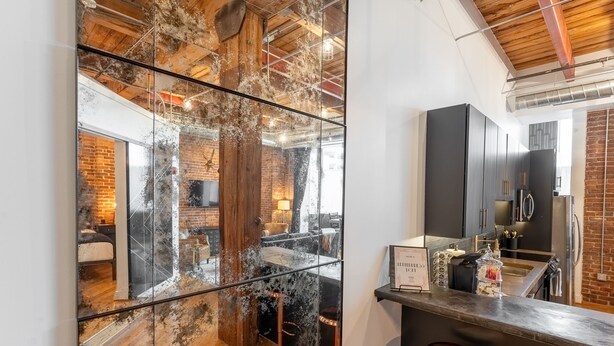 A modern kitchen with dark cabinets, a stainless steel refrigerator, and a bar area with stools.