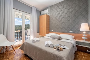 A hotel room with a bed, a nightstand, a lamp, a chair, and a view of the outdoors. - Pool Villa Sine /w Panoramic Sea View (Marina)