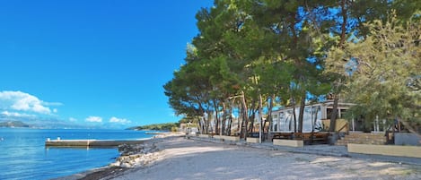 A beach with a row of cabins, a dock, and a clear blue sky.