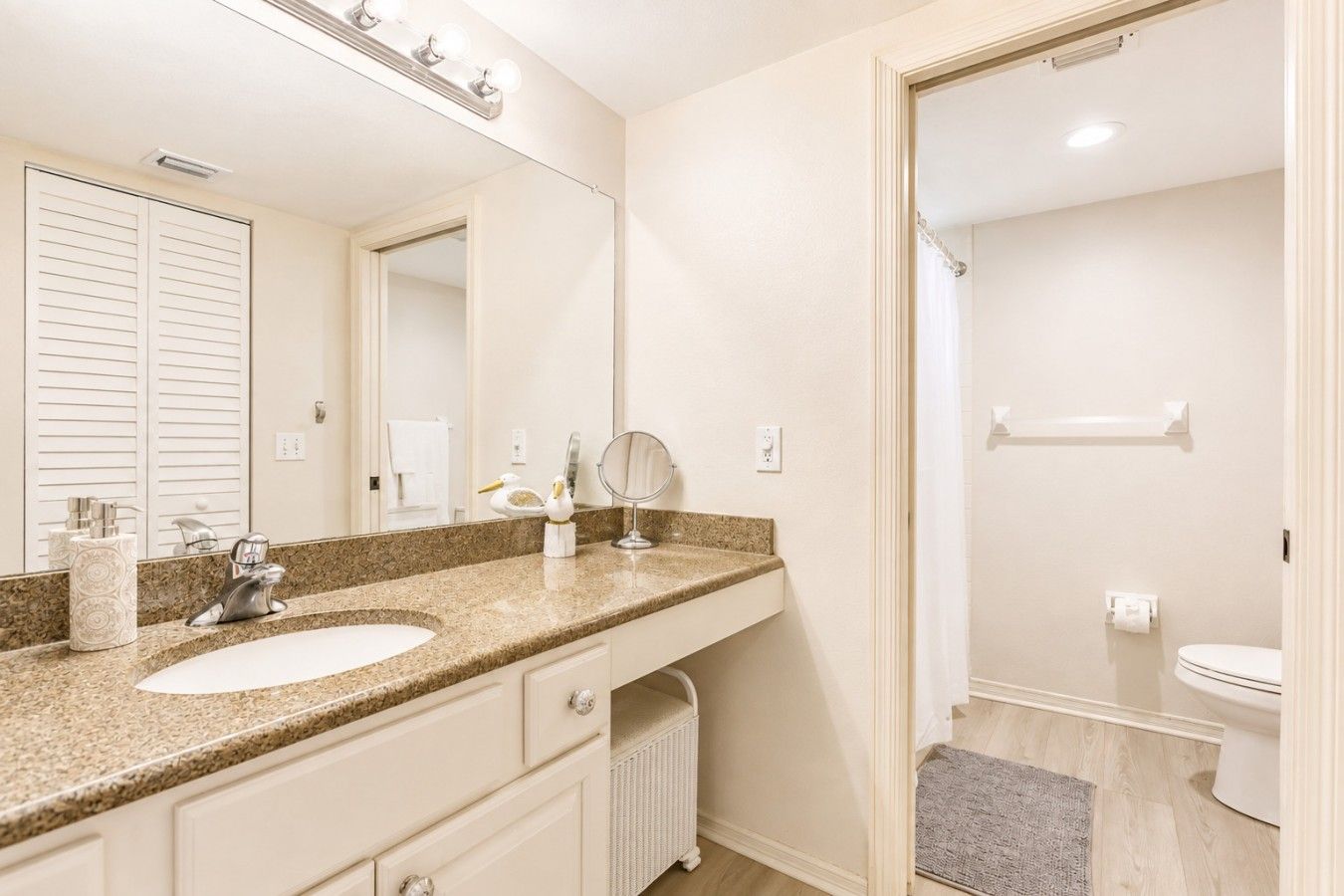 A bathroom with a double sink vanity, a mirror, a towel rack, and a shower area.