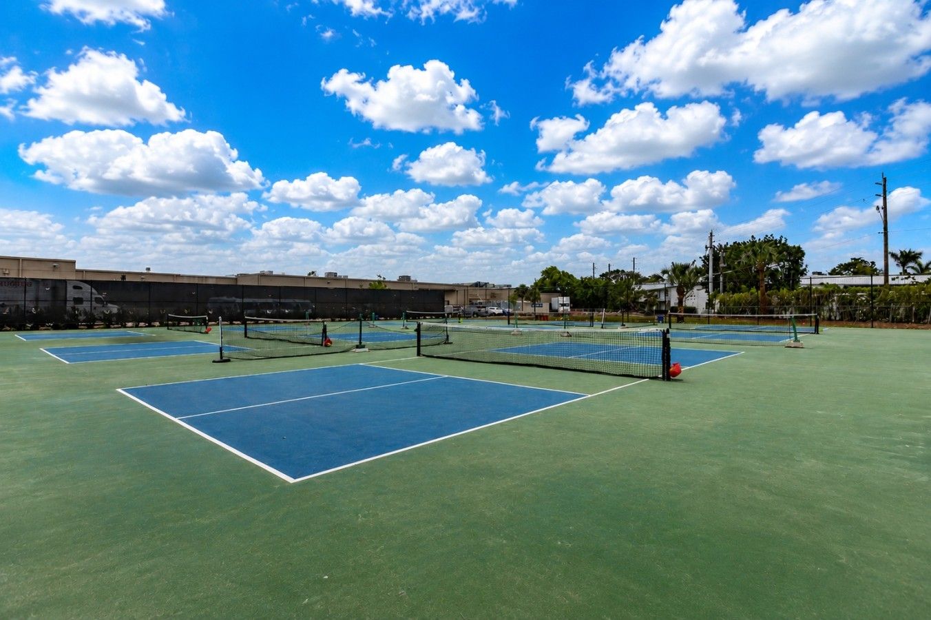A tennis court with multiple courts, a net, and a clear sky.