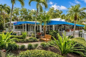 Un restaurant doté d’une terrasse, entouré de palmiers et de plantes tropicales.