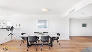 Et moderne spiseområde med et hvidt bord, sorte stole og en fritsvævningsventilator.