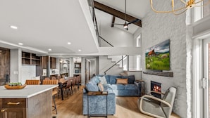 Un salon moderne avec un canapé bleu, une cheminée et un coin repas doté de meubles en bois.