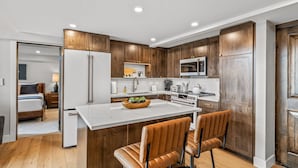 Une cuisine moderne avec des meubles en bois, des appareils en acier inoxydable et un îlot central doté de tabourets de bar.