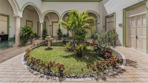 Un patio con un jardín circular, plantas en macetas y una piscina.