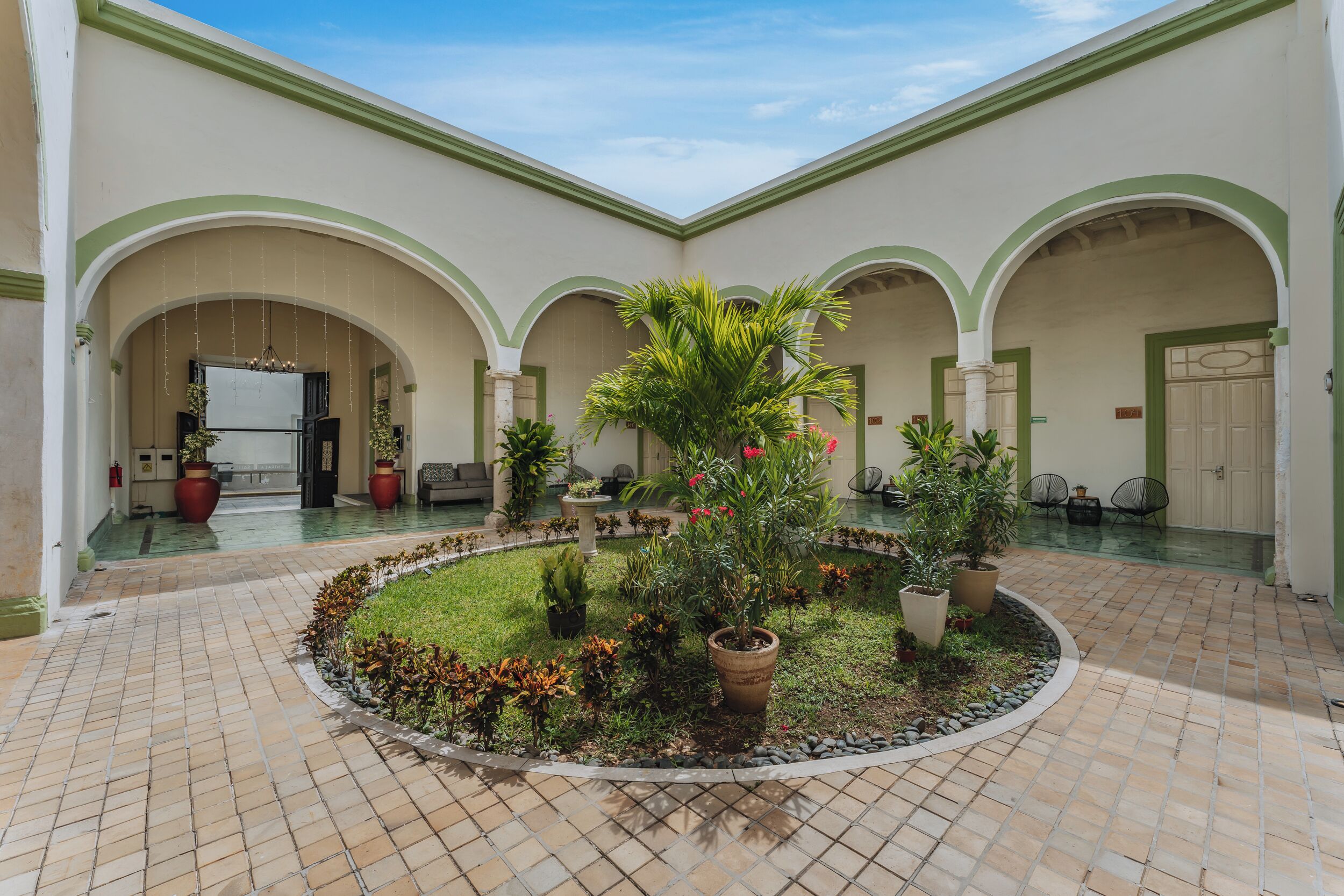 A courtyard with a central garden, tiled floor, and arched doorways.