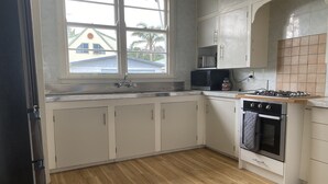 Une cuisine avec des meubles blancs, un évier en acier inoxydable, un four à micro-ondes, une cuisinière et un four.