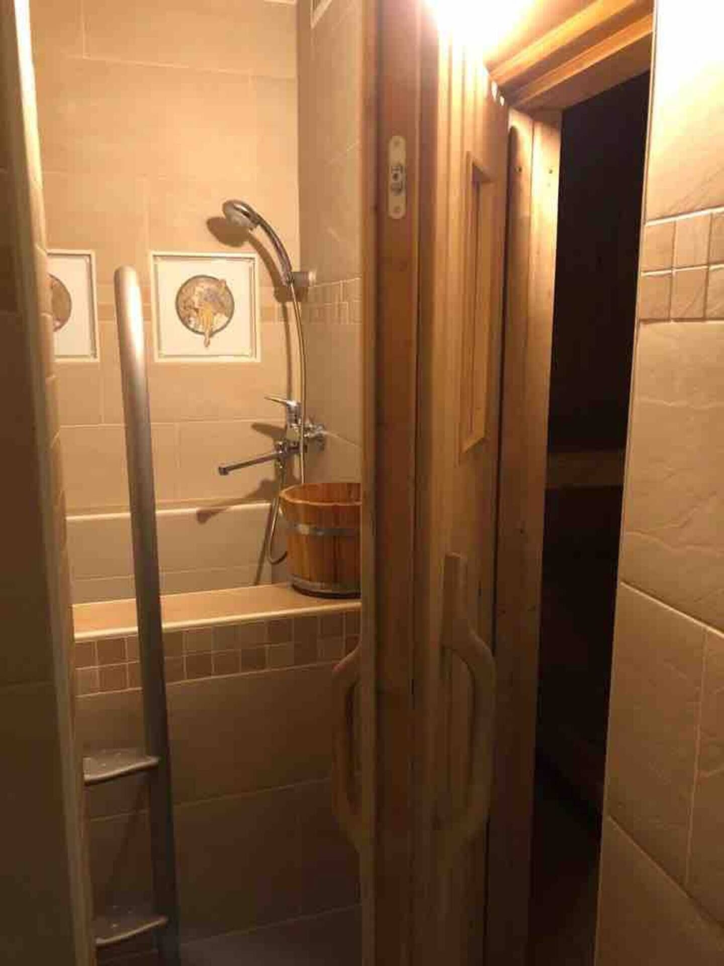 Ein kleines Badezimmer mit einer Badewanne, einer Dusche und einer Holztür.