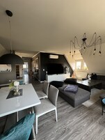 Un loft moderno con comedor, sala de estar con sofá y mesa de centro, y una cocina al fondo.