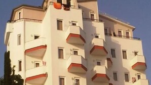 Een meerhoog hotel met balkons, een plat dak en een heldere lucht.