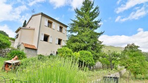A two-story building with a tiled roof, surrounded by lush greenery and trees. - RENTALS-06 NOELIE'S HOUSE - 300M RIVIERE 30mn NICE CANNES ANTIBES (Le Bar-sur-Loup)