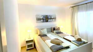 A bedroom with a large bed, bedside tables, a ceiling light, and a painting on the wall. - Ocean Golf & Country Club J&K A4 (Oasis del Sur)
