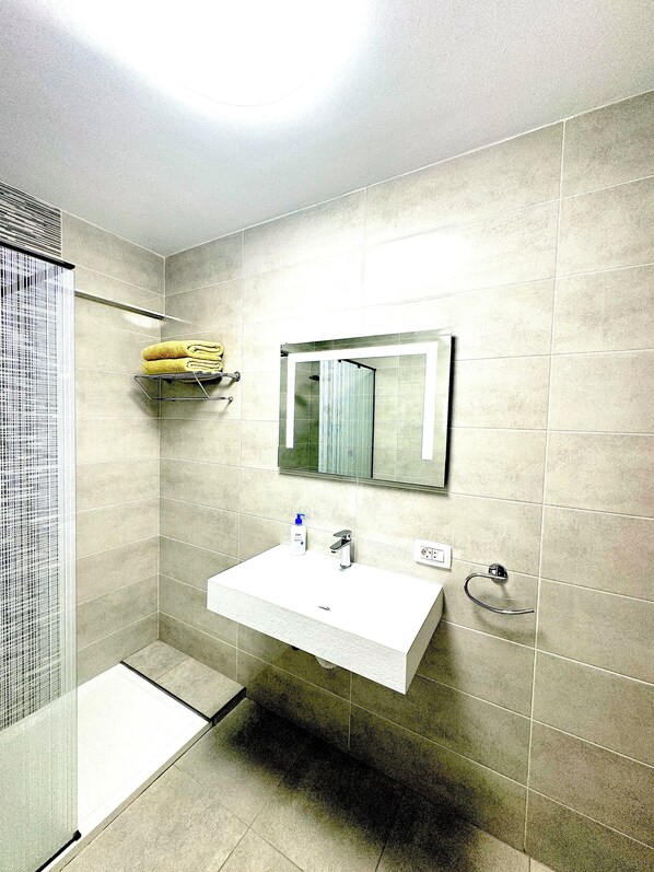 A bathroom with a white sink, a mirror, and a shower.