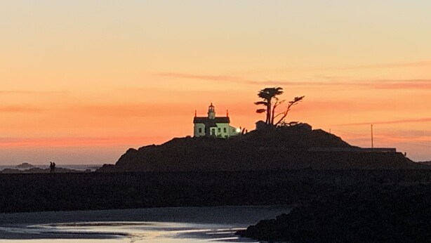 En kustvy med en fyr på en kulle, med utsikt över havet.