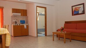 Un espacio habitable compacto con kitchenette, sofá y comedor.