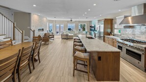 A spacious kitchen with a large island, wooden bar stools, and a view to the outside.