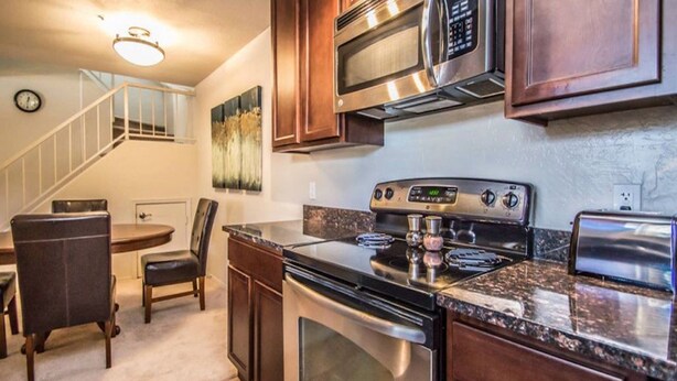 A kitchen with a stainless steel stove, microwave, and toaster. There is a dining area with a table and chairs. - Great North Scottsdale Condo! (Scottsdale)