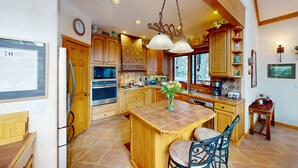 A spacious kitchen with wooden cabinets, a central island, and modern appliances. - Views | Hot Tub | Fireplace | Scenic Serenity (Angel Fire)