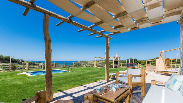 Een houten pergola met een zwembad en een terras.